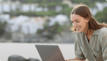 Mujer feliz con su ordenador portátil disfrutando de la fibrade Vodafone en su segunda residencia